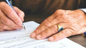 Person signs a payroll funding contract with a pen on a conference room table